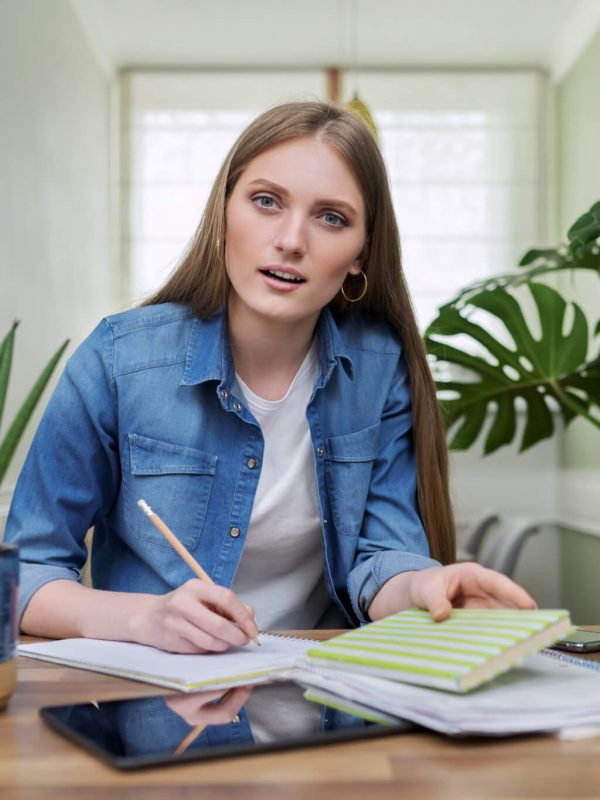 online-training-female-teenager-sitting-at-home-looking-at-webcam-canadian-flag-on-table.jpg